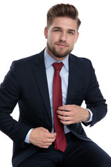 chaming young businessman fixing tie on white background