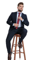 confident young businessman arranging tie on white background