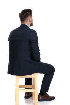 back view of young businessman sitting on wooden chair