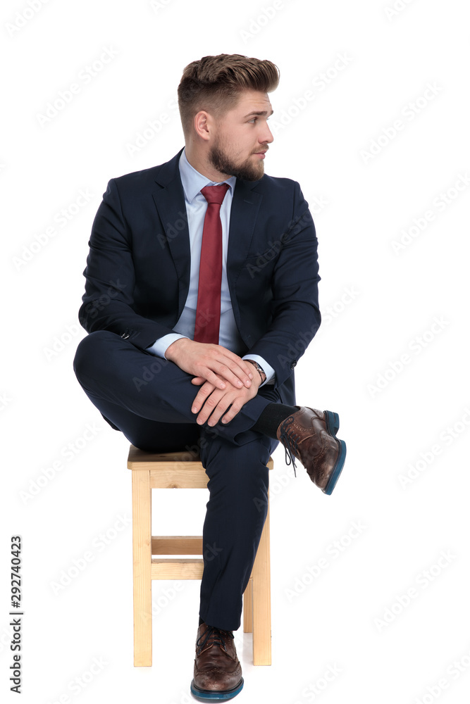 Poster impatient young businessman sitting on wooden chair