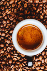 Roasted coffee beans with cup of espresso on dark background