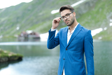 smart casual fashion model fixing glasses outdoor in nature