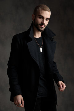 casual young man wearing longcoat on grey background