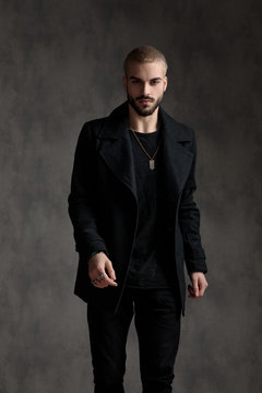 handsome fashion man wearing black longcoat in studio