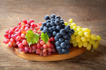 mix of ripe grapes with leaves on a wooden board