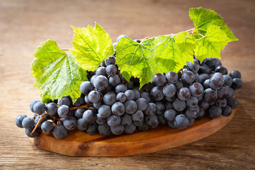 fresh blue grapes with leaves on a wooden board