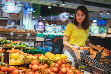 woman choosing vegetables from store shelf grocery shopping