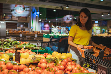 woman choosing vegetables from store shelf grocery shopping