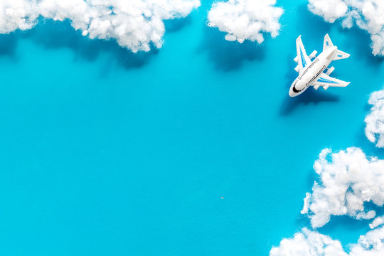 Fly by plane concept. Airplane model and clouds on blue background top view frame space for text