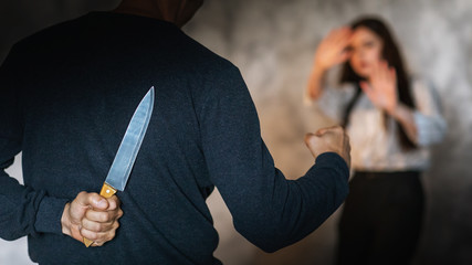 Concept on the topic of domestic violence. A man with a knife behind his back in a room threatens a...