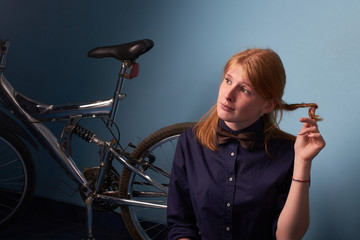 Plakat pretty girl sitting on the floor of a bike shop near a bike