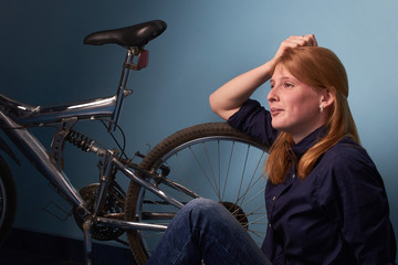 Obraz na płótnie Canvas pretty girl sitting on the floor of a bike shop near a bike
