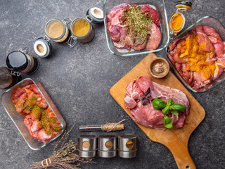 Raw meat background. with a variety of herbs and spices. On the grey concrete table. copy space