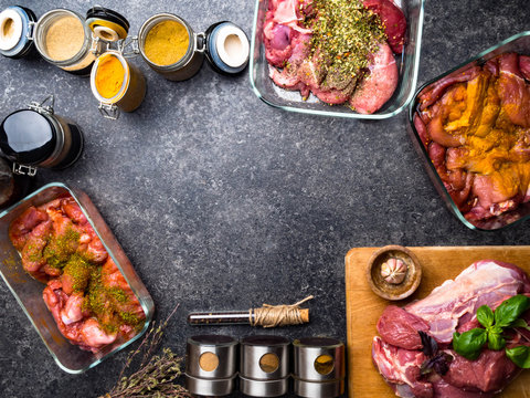 Raw meat background. with a variety of herbs and spices. On the grey concrete table. copy space