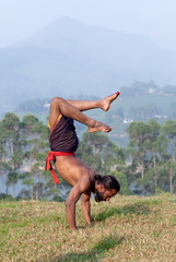 Indian man doing handstand outdoors in Kerala, South India