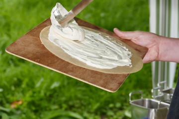 Flammkuchen beim zubereiten mit Speck, Zwiebeln und creme fresh