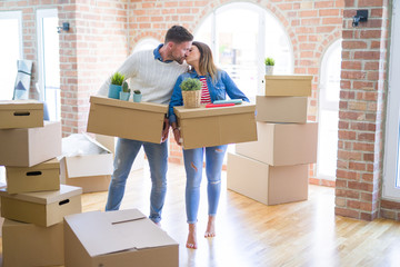 Fototapeta na wymiar Young beautiful couple moving cardboard boxes and kissing at new home