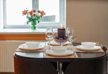 Close-up of served table in apartment. Wine glasses and crockery.