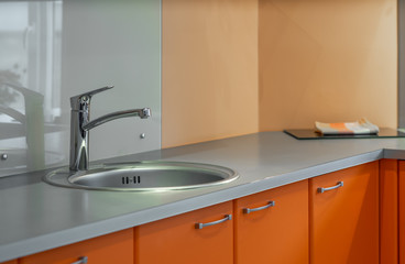 Close-up of sink in modern orange kitchen set.
