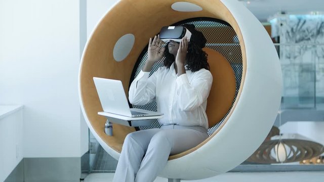 Focused businesswoman with laptop and vr headset. Serious young African American businesswoman using laptop computer and virtual reality headset. Technology concept