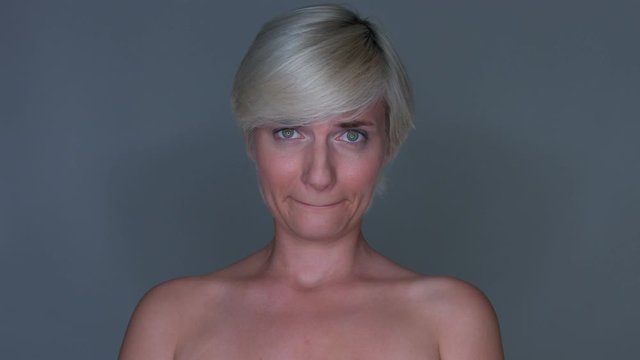young blond model girl looks into the camera and pinches her lips together.