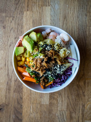 traditional Hawaiian dish, with seafood, noodles, seeds, avocado, pineapple, onion, salad, with sauces, on wooden background, selective focus