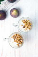 Crispy muesli in a glass with fresh yogurt and fresh figs, morning Breakfast, light snacks. Breakfast cereals isolated on white background, selective focus, top view