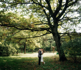 Portrait of kissing couple in the garden under huge oak