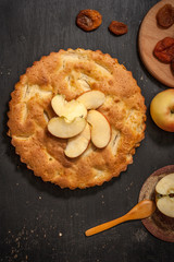 Charlotte apple pie on a black wooden table with slices of red apples. Top view.