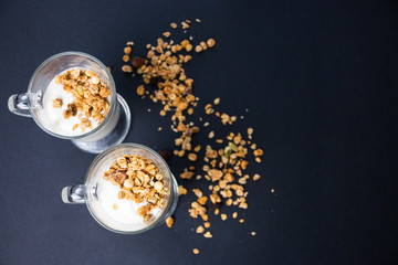 Crispy muesli in a glass with fresh yogurt, morning Breakfast, light snacks. Breakfast cereals isolated on dark background, selective focus, top view