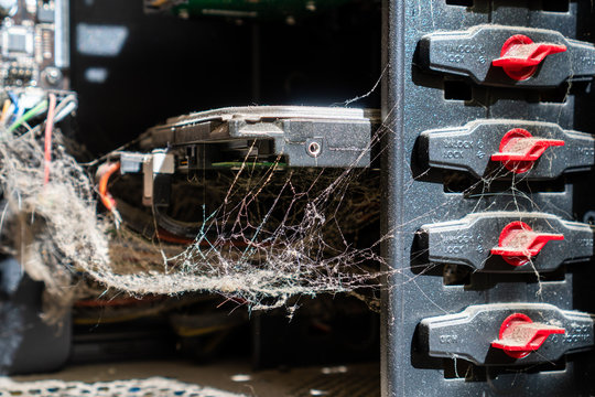 Closeup of a computer hard drive mounted on a rack covered in dust and spider webs. Outdated and abandoned technology. Server vulnerability concept.