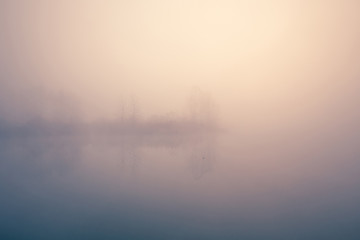 Obraz na płótnie Canvas Beautiful foggy morning. Lake coast. Fog over autumn lake water.