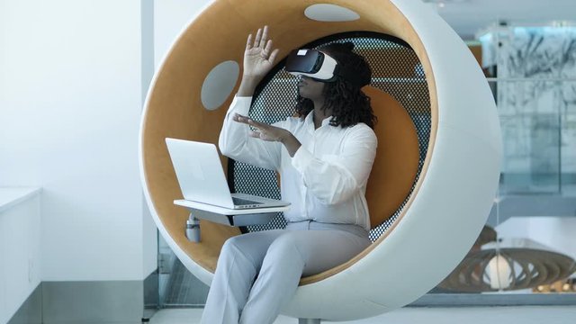 Focused young businesswoman with laptop and vr headset. Serious young African American businesswoman using laptop computer and virtual reality headset. Technology concept
