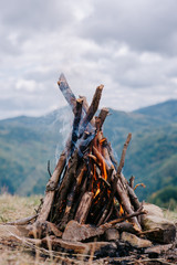 Closeup vertical image of a bonfire in autumn time on background mountains. Concept adventure active vacations outdoor hiking sport