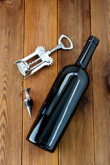 A bottle of wine with corckscrew, wooden rustic background. Flat lay wine drink with copy space.