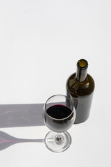 Glass and bottle of wine with dark shadows isolated on a white background