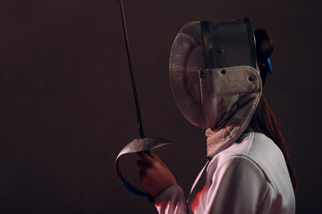 Fencer woman in mask profile portrait with fencing sword.