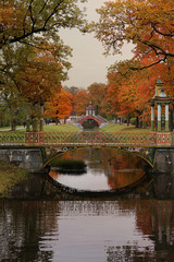 Fototapeta premium Russia, St. Petersburg, September 28, 2019, Alexander Park. In the photo - an autumn pond with fallen leaves and the Cross Bridge. The beauty of the September forest