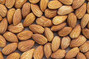 Background in the form of unshell almonds on a brown wooden background
