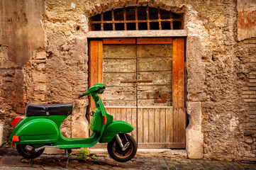 Green scooter near an old wall in Rome, Italy. Exterior, architecture and landmark of ancient streets in Rome.