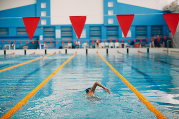 Young woman swimmer swims in swimming pool