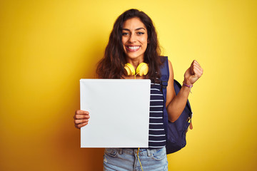 Fototapeta na wymiar Young beautiful student woman holding banner standing over isolated yellow background screaming proud and celebrating victory and success very excited, cheering emotion