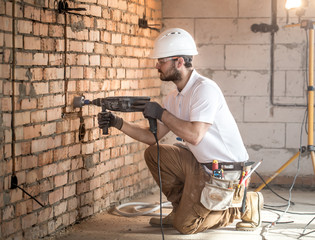 Handyman uses jackhammer, for installation, professional worker on the construction site. The...