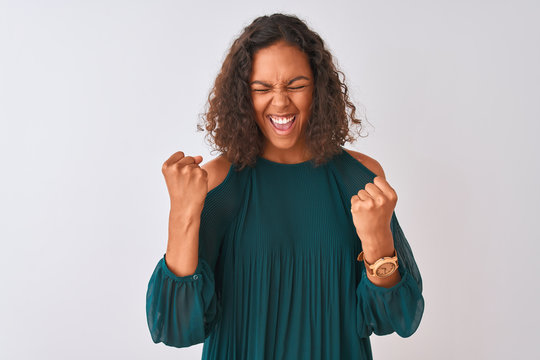 Young brazilian woman wearing green t-shirt standing over isolated white background very happy and excited doing winner gesture with arms raised, smiling and screaming for success