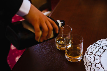 a man pours alcohol in two glasses