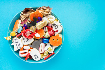 Halloween Jack o Lantern candy bowl with candy and halloween cookies Trick or Treat on blue background