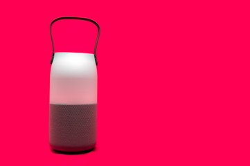 A wireless, voice controlled smart speaker that also functions as a lantern that changes to multiple colors. The bluetooth device is isolated in a red background.