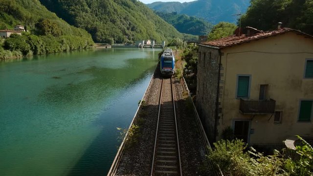 A train crosses the Serchio river under the Ponte del Diavolo, also known as Ponte della Maddalena, Borgo a Mozzano, Tuscany, Italy
