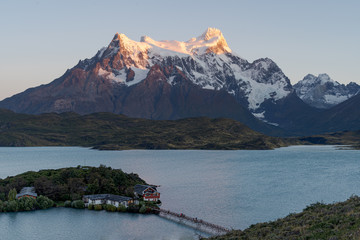 Paine Grande light up by early morning sunlight with estancia pehoe in the foreground