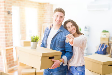 Fototapeta na wymiar Beautiful young couple hugging in love and showing keys of new house, smiling happy moving to a new apartment
